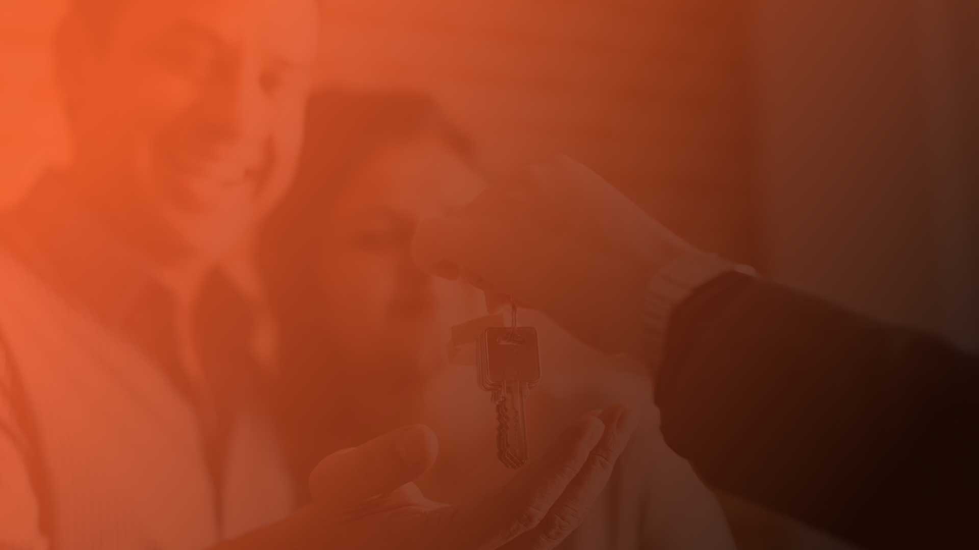 Keys handed to smiling new homeowners with orange overlay background